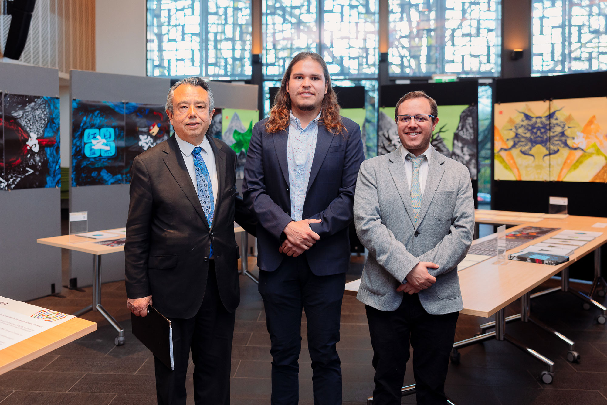 Three visitors standing together among the exhibition’s artwork and books