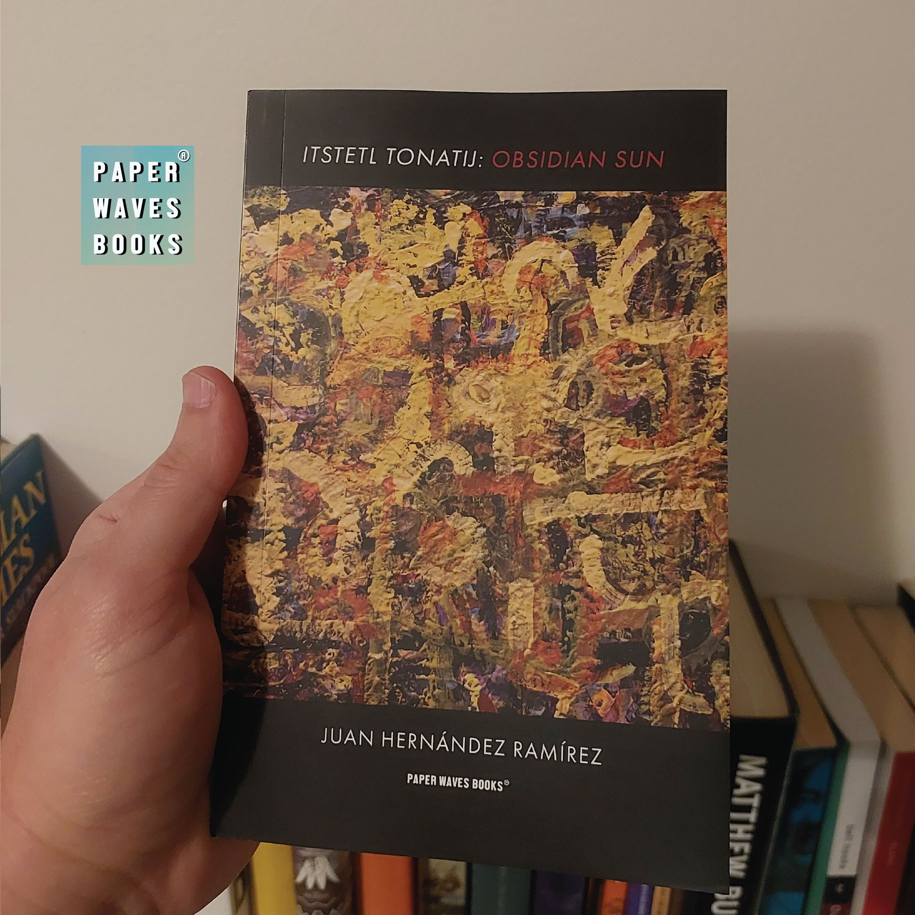 The front cover of Itstetl Tonatij: Obsidian Sun held in one hand